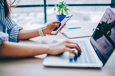 Woman Using Cell Phone at Computer